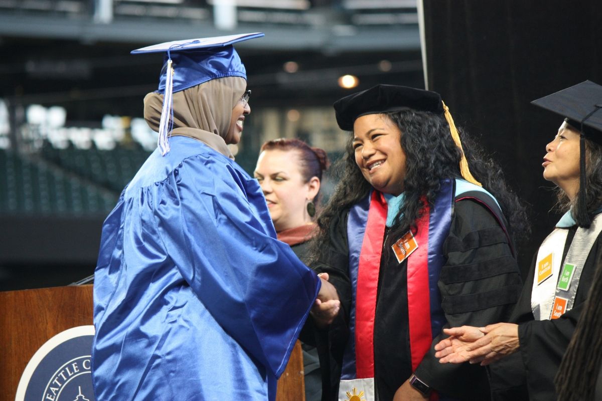 President Rosie Rimando-Chareunsap shakes hands with a South Seattle College graduate. 