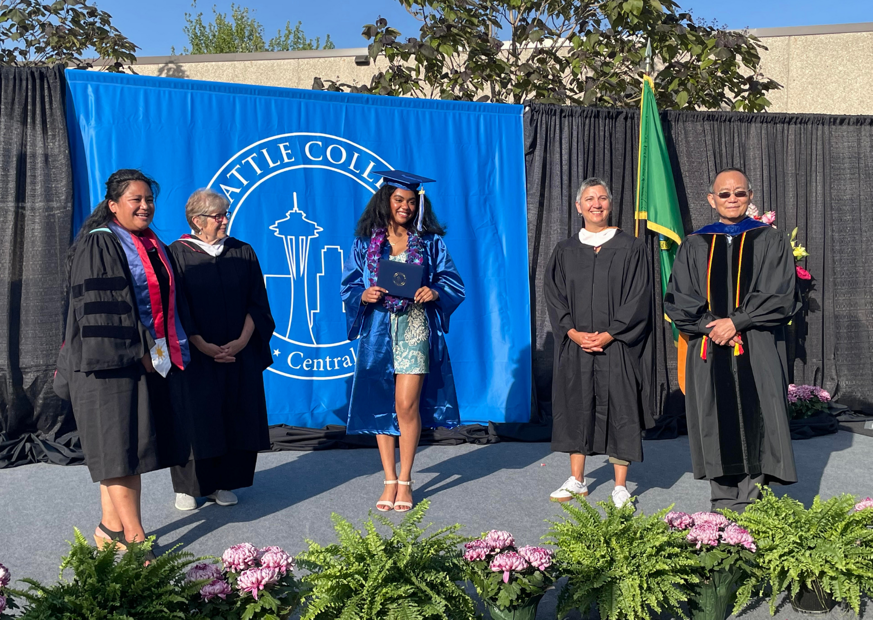 Graduate posing for photo with college leadership 