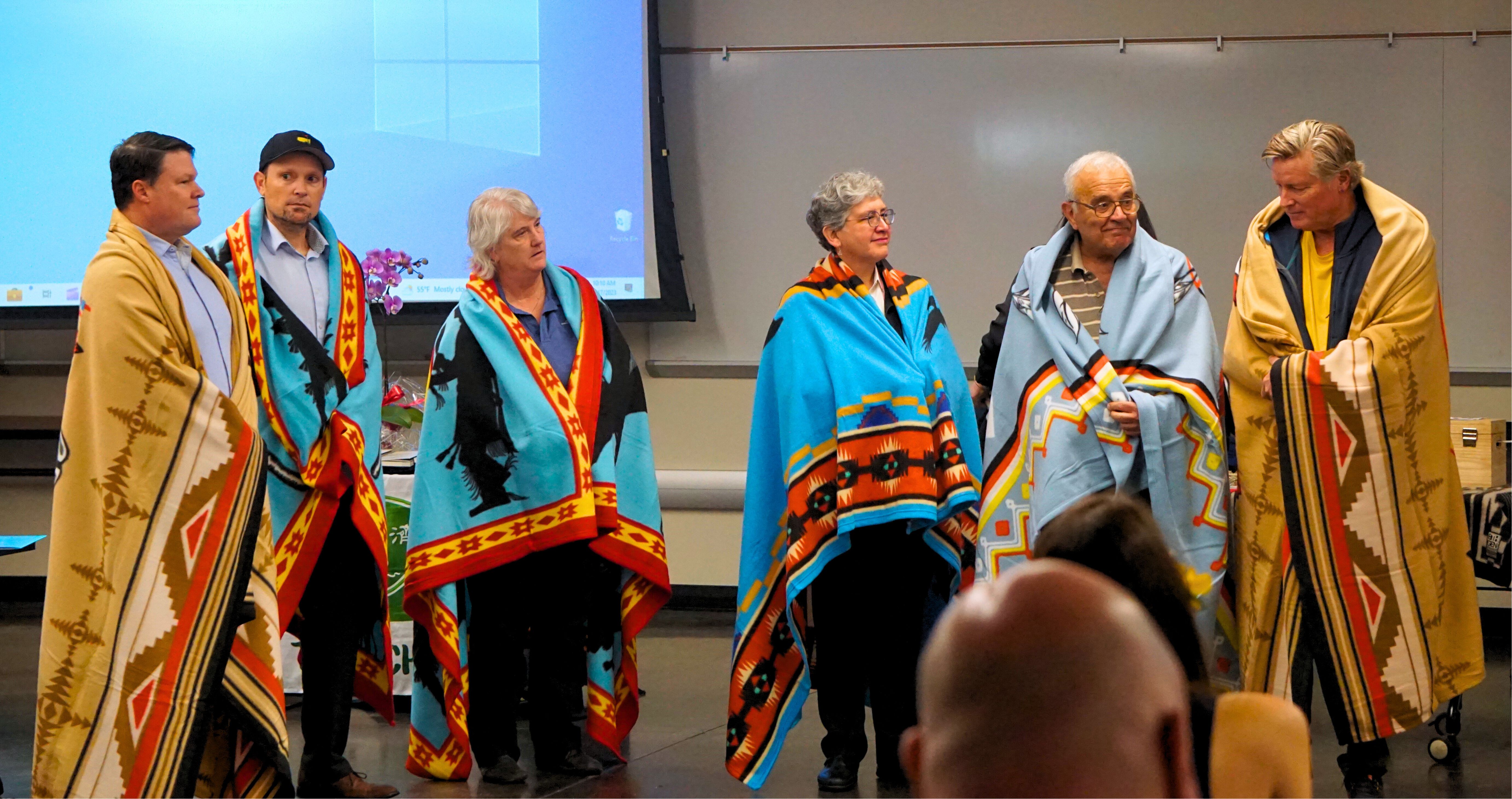 JIS speakers wear tribal blankets at a graduation ceremony.